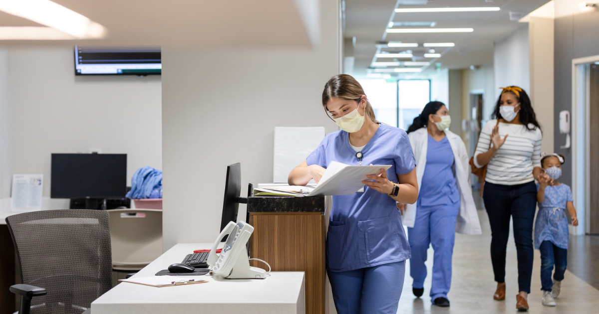 A picture of a nurse standing at a nurse's station