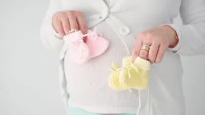 Pregnant woman holding two sets of booties in front of her stomach