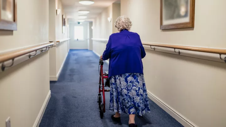 Senior woman walking down a hallway with a walker