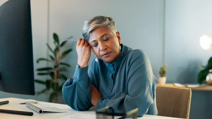 Middle-aged woman looking stressed at her desk