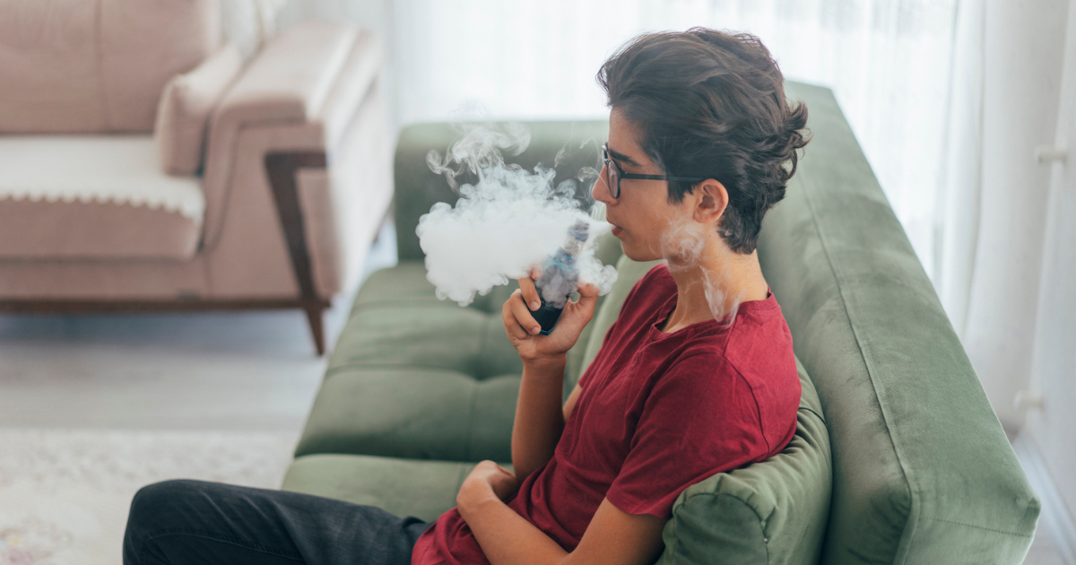 Teen sitting on couch, vaping