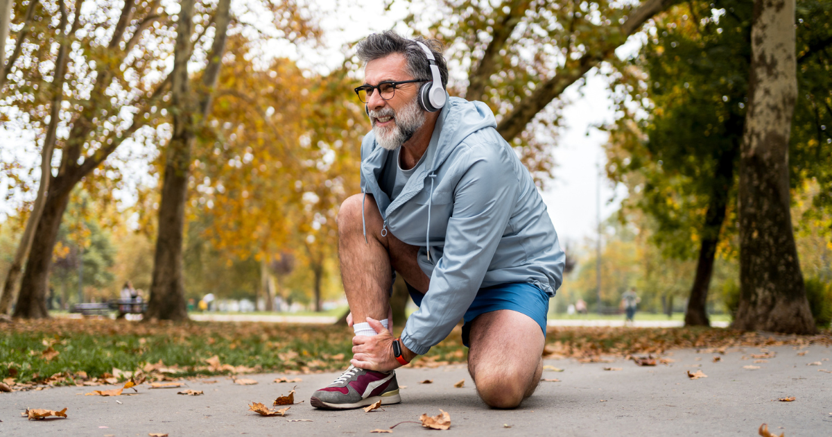 Man kneeling, holding his ankle in pain