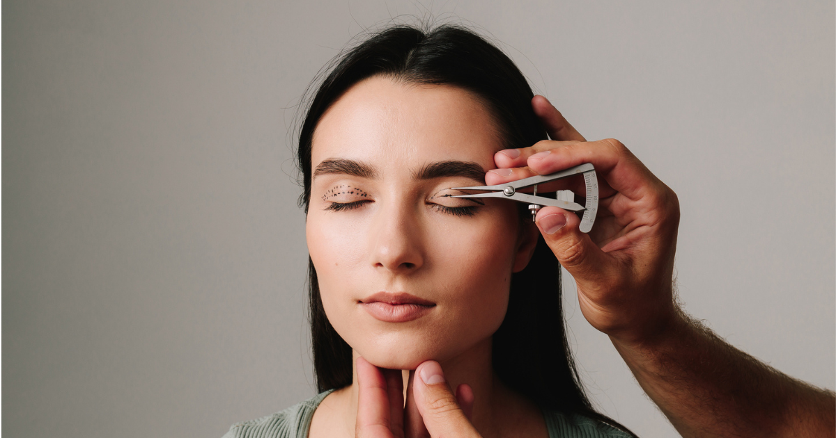 Surgeon measuring distance on woman's eyelid for blepharoplasty