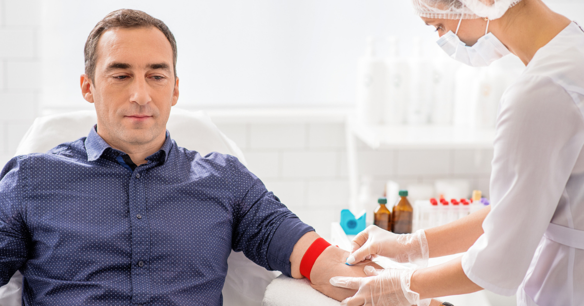 Nurse taking blood sample from man's arm
