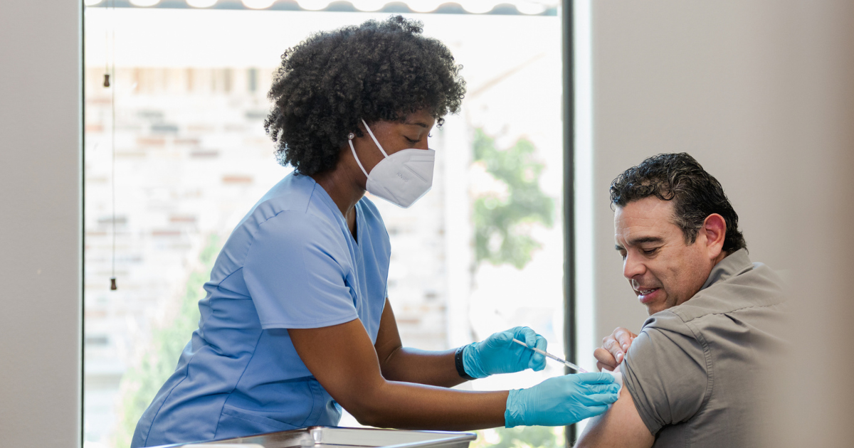 Nurse in protective mask and gloves gives man vaccination