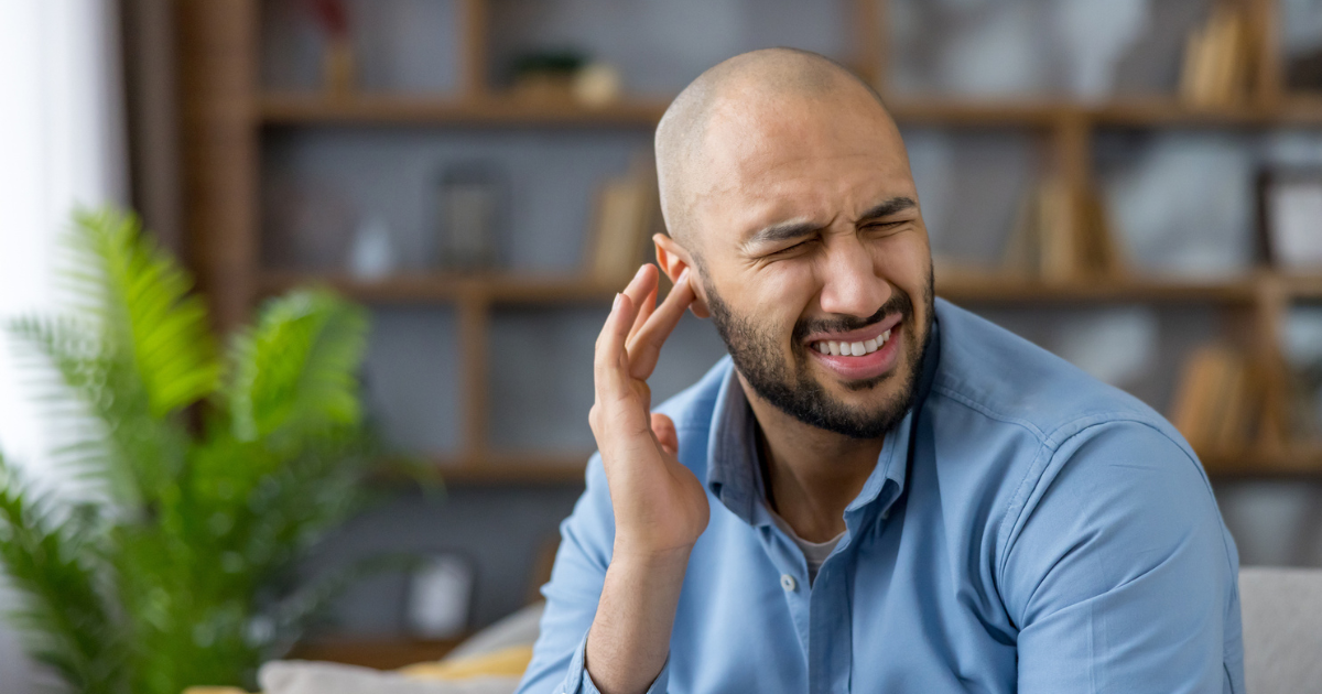 Man holding ear in discomfort