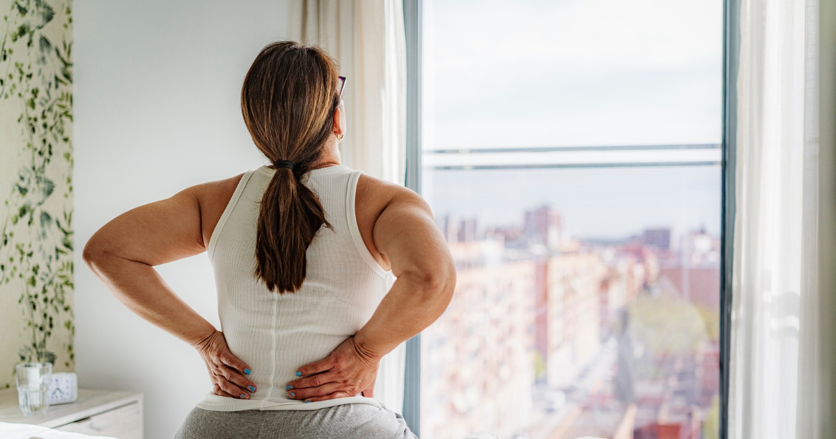 Woman sitting in bed with back pain