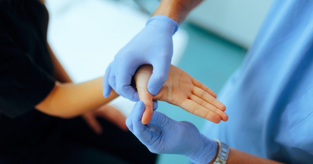 Close up of gloved hands inspecting patient's thumb