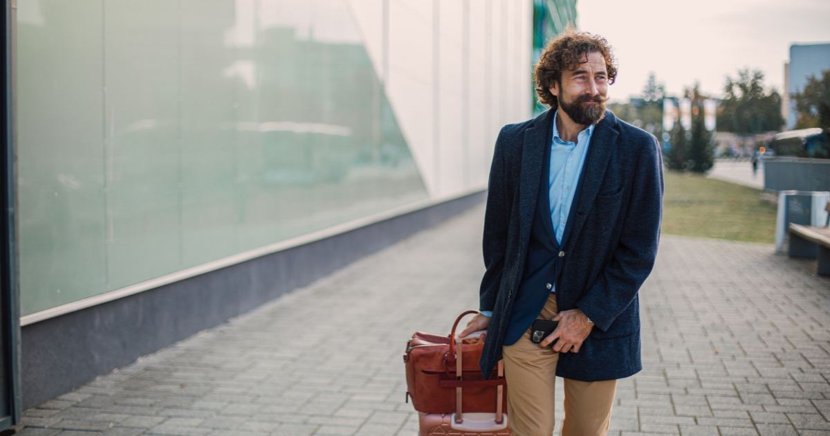 Man with suitcase holding groin