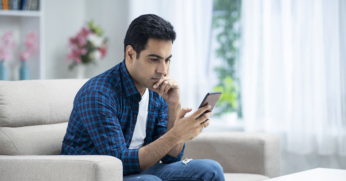 Man sitting on the couch looking at his phone