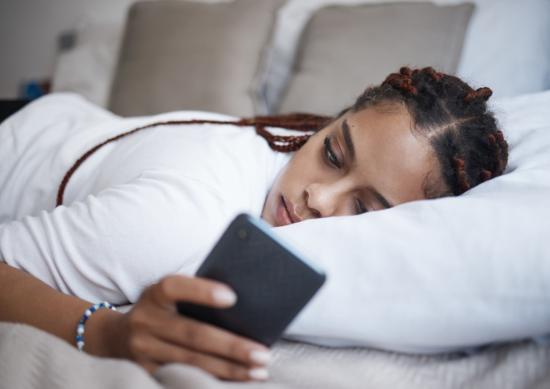 Depressed woman laying on the couch on her phone