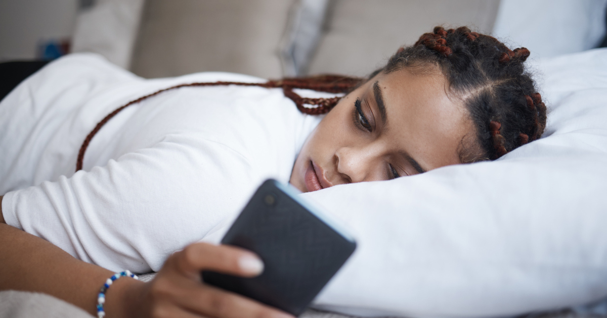 Depressed woman laying on the couch on her phone