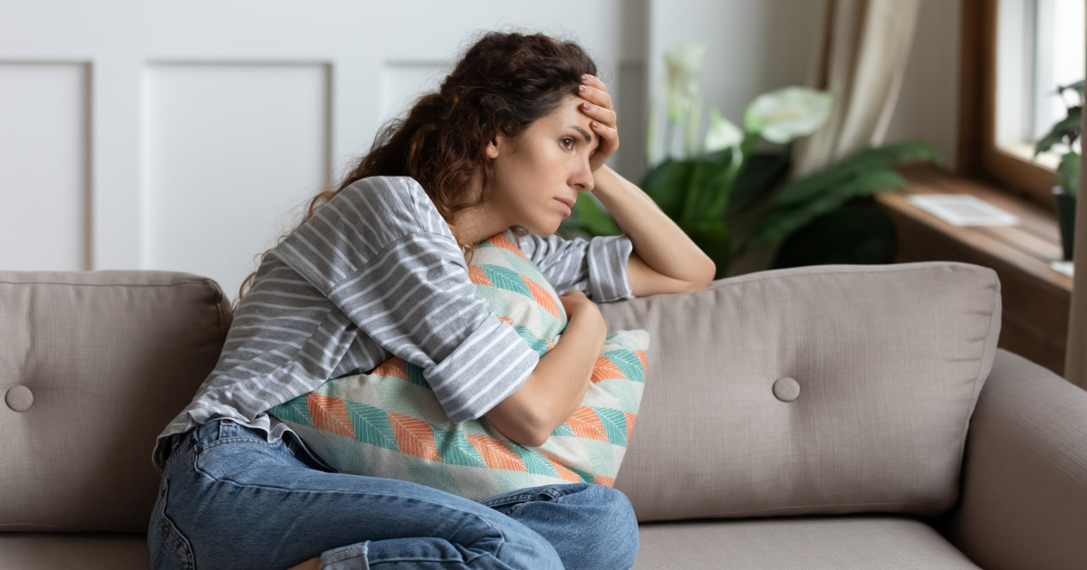 Young woman sitting on the couch looking out the window