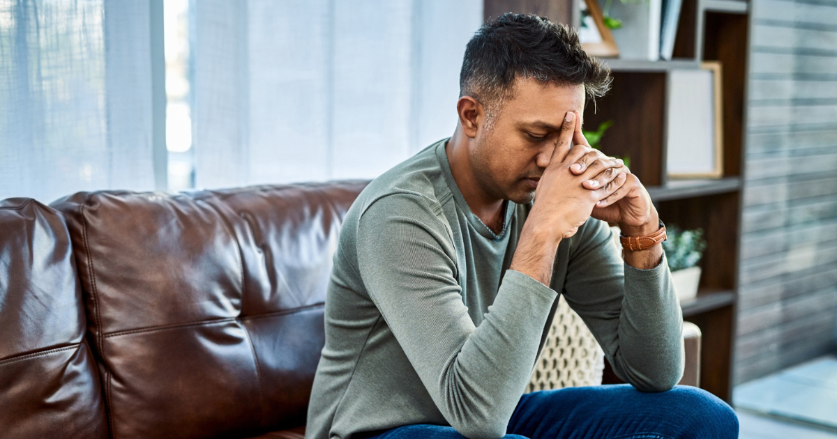 Man sitting on couch with head in hands