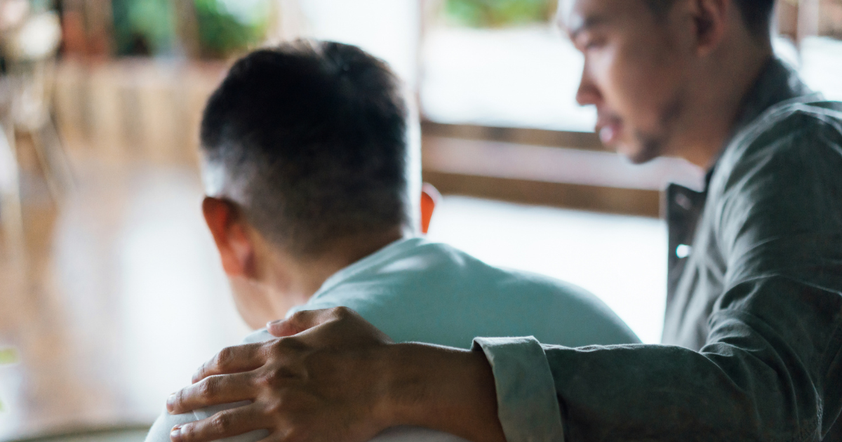 Man with his arm around an older man