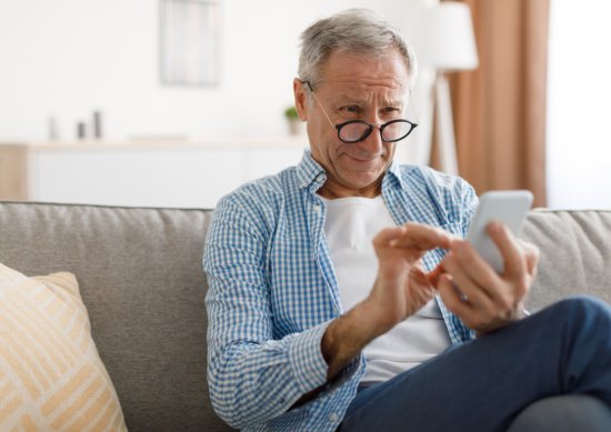 Picture of a man with glasses looking at his cellphone