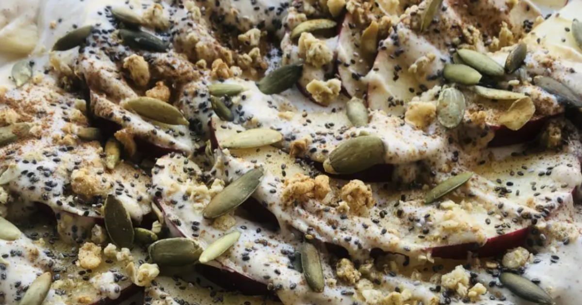 Plate of sliced apples covered in seeds, Greek yogurt and honey