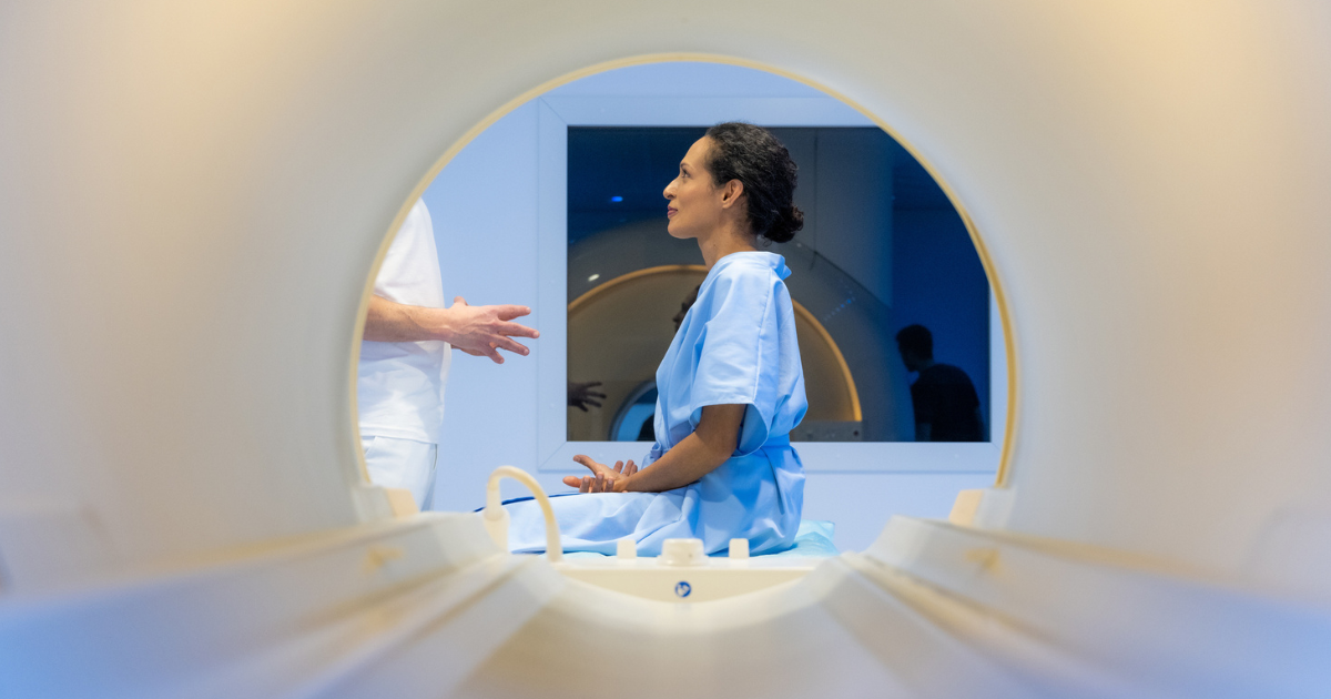 Woman sitting on MRI table talking to provider