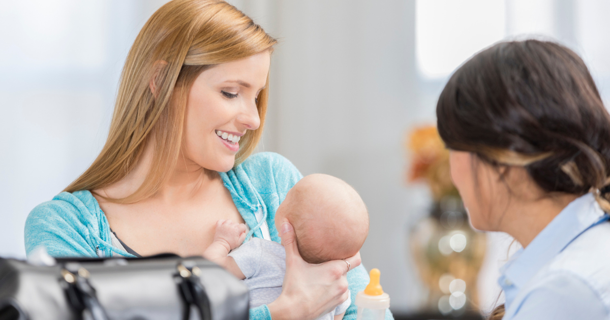 Woman holding an infant talking to lactation consultant