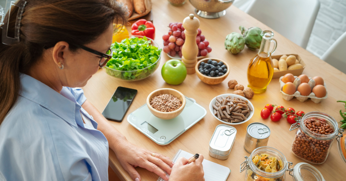 Woman planning, writing weekly meals on a meal planner note pad