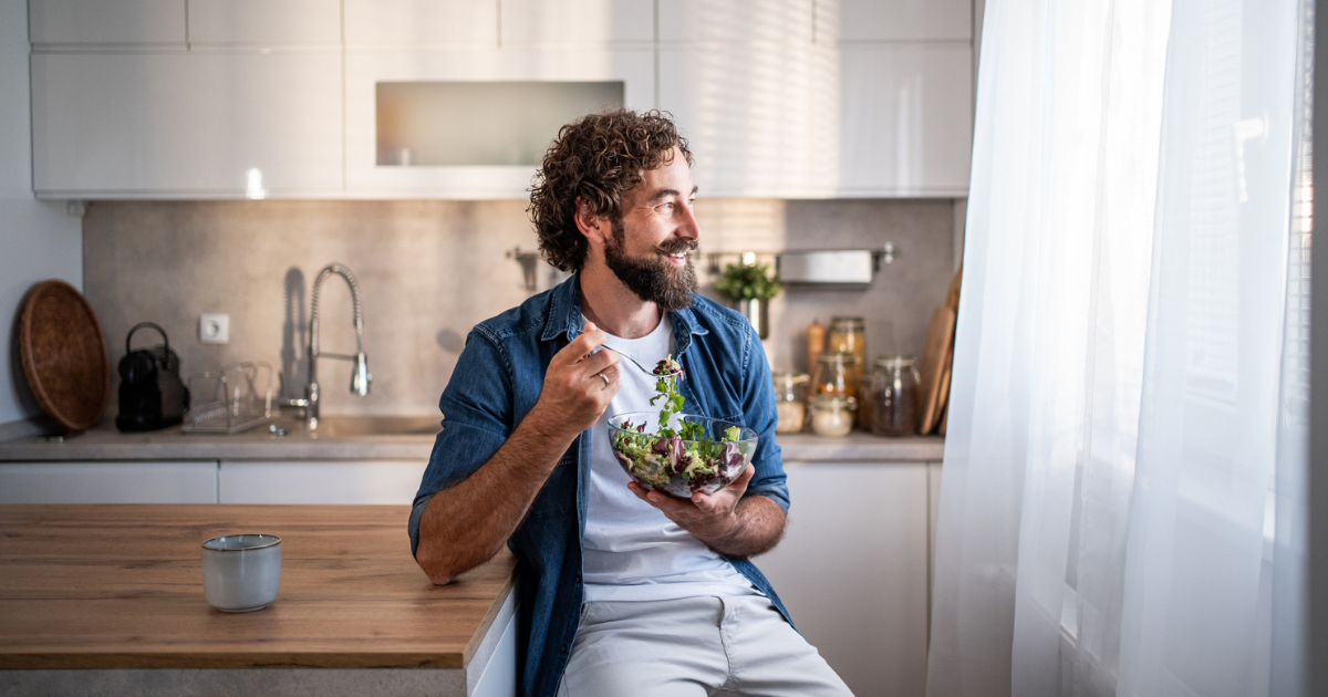 Man sitting in kitchen eating a salad