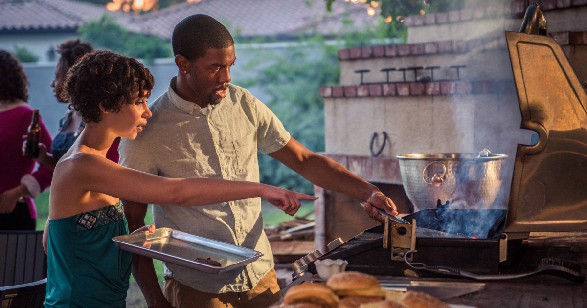 Man and woman standing at grill