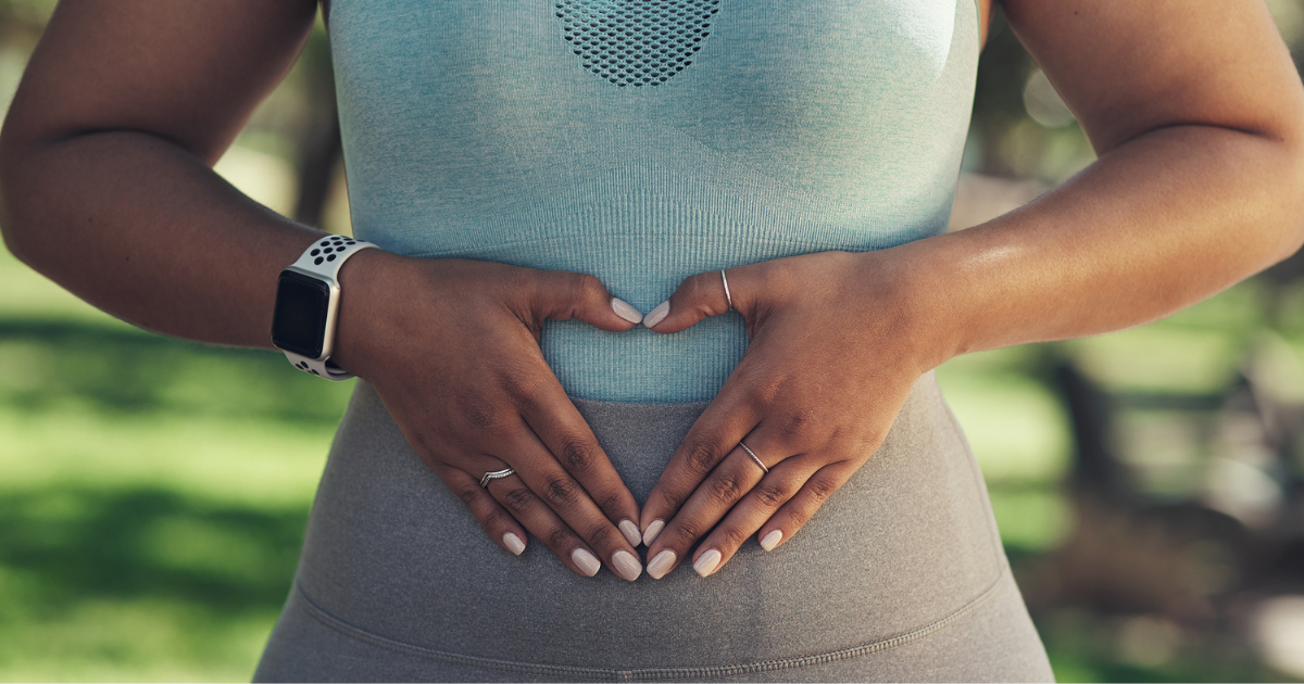 Close up of woman making a heart with her hands over her stomach