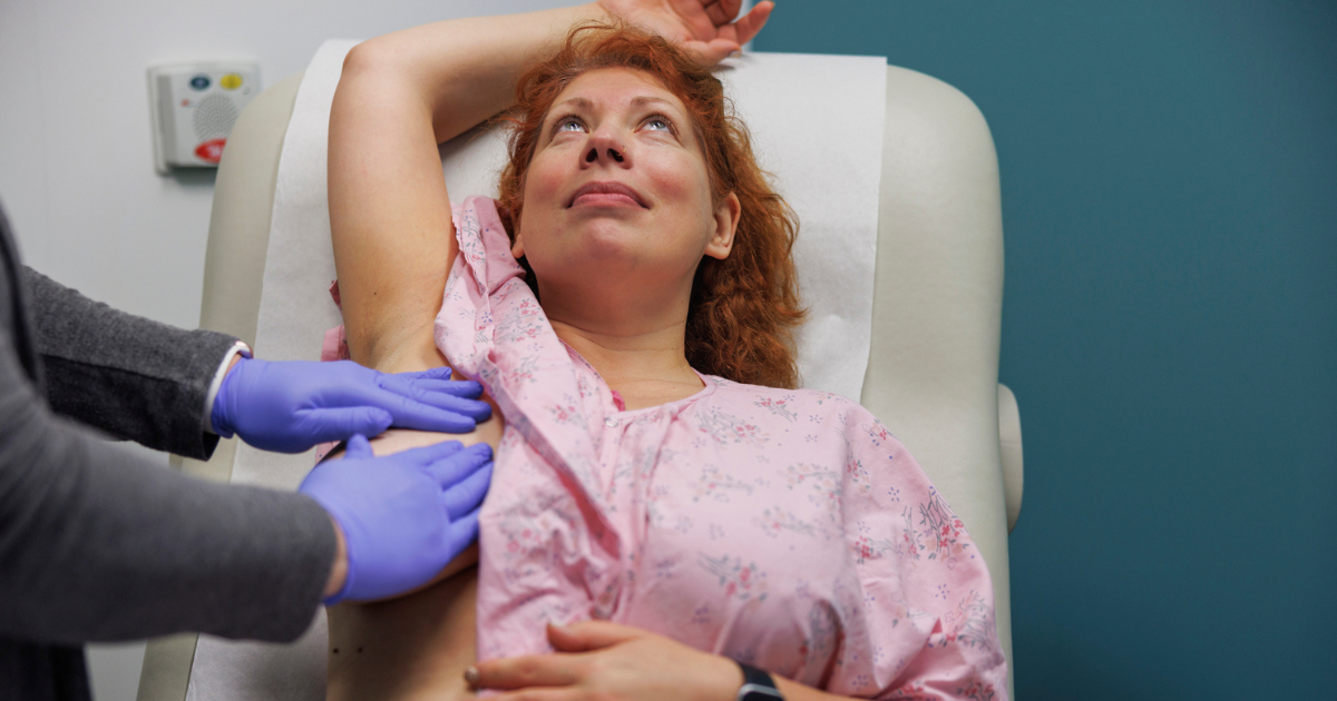Doctor feeling woman's lymph nodes near breast