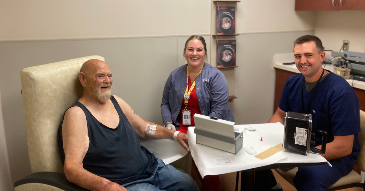 Craig Johnson, MD, Nuclear Medicine (right), and Beth McCaw, lead nuclear medicine technologist (center), administer the initial PLUVICTO dose to Phil Painter (left). 