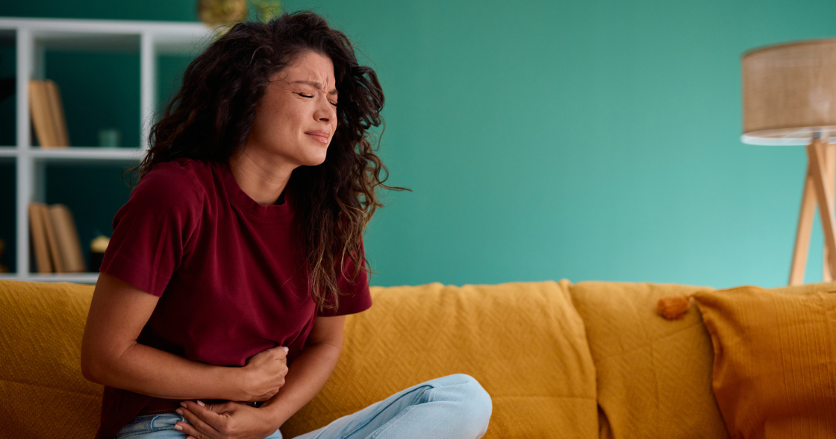 Woman sitting on couch holding stomach