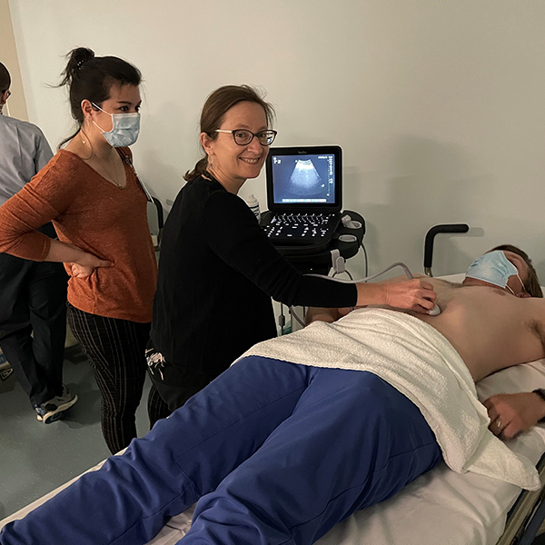 Two people, one smiling using an ultrasound on a man lying down