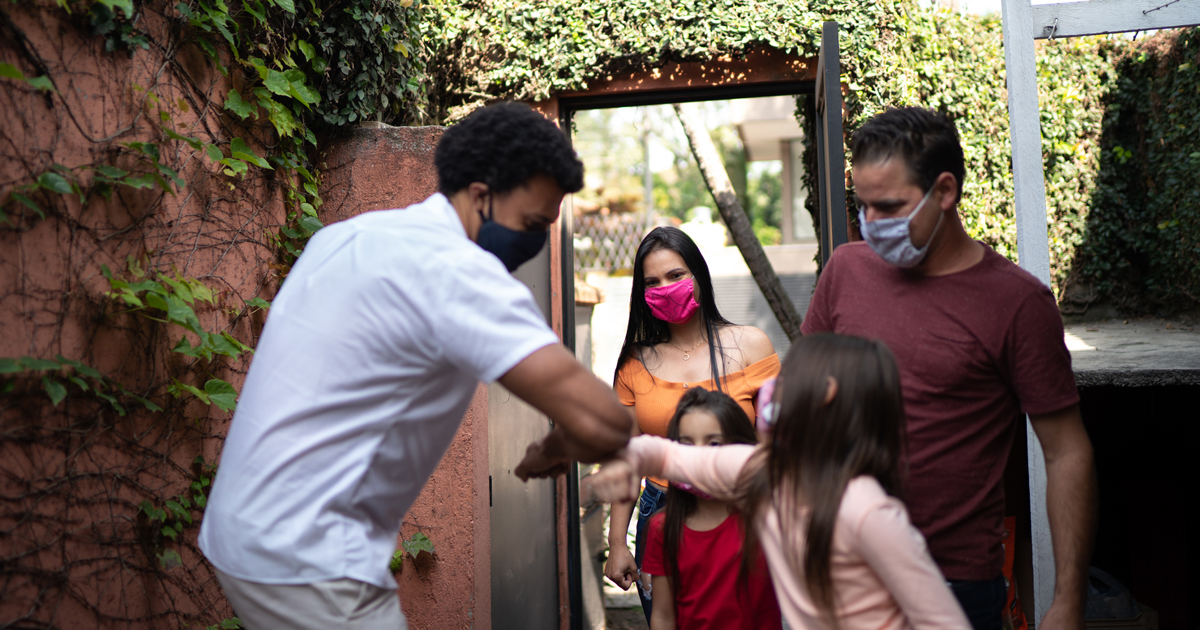 People wearing masks touching elbows