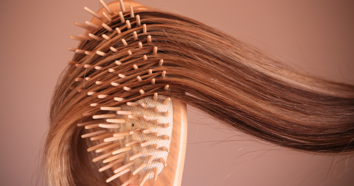 Close up of a hair brush brushing long brown hair