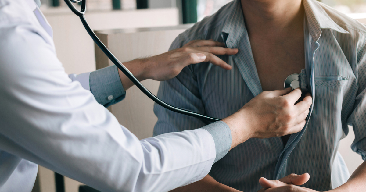 Doctor listening to man's heart