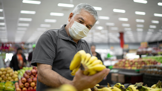 picture of a man grocery shopping in a face mask