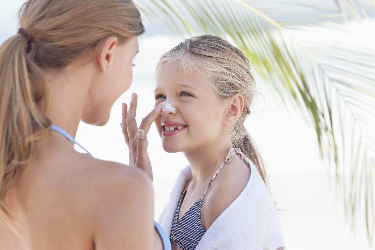 Woman putting sunscreen on her daughter