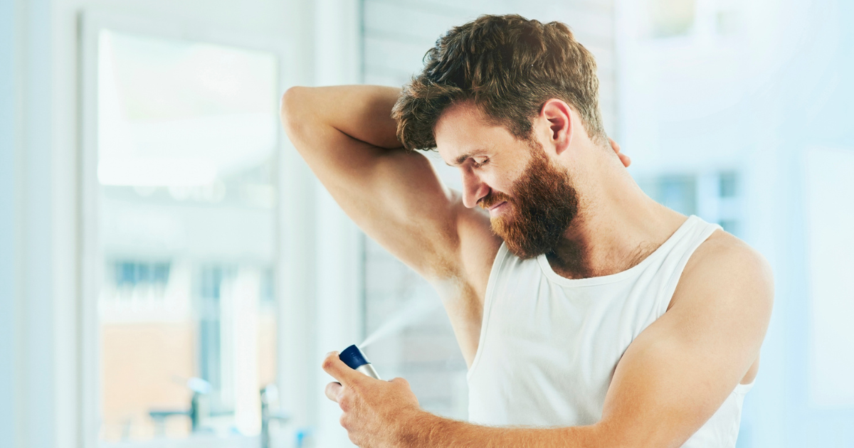 Man spraying deodorant on his armpit