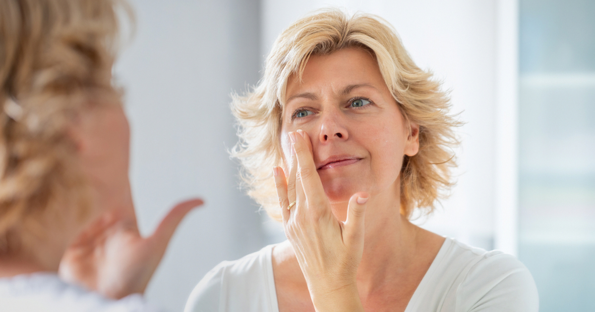 Woman applying cream to her face