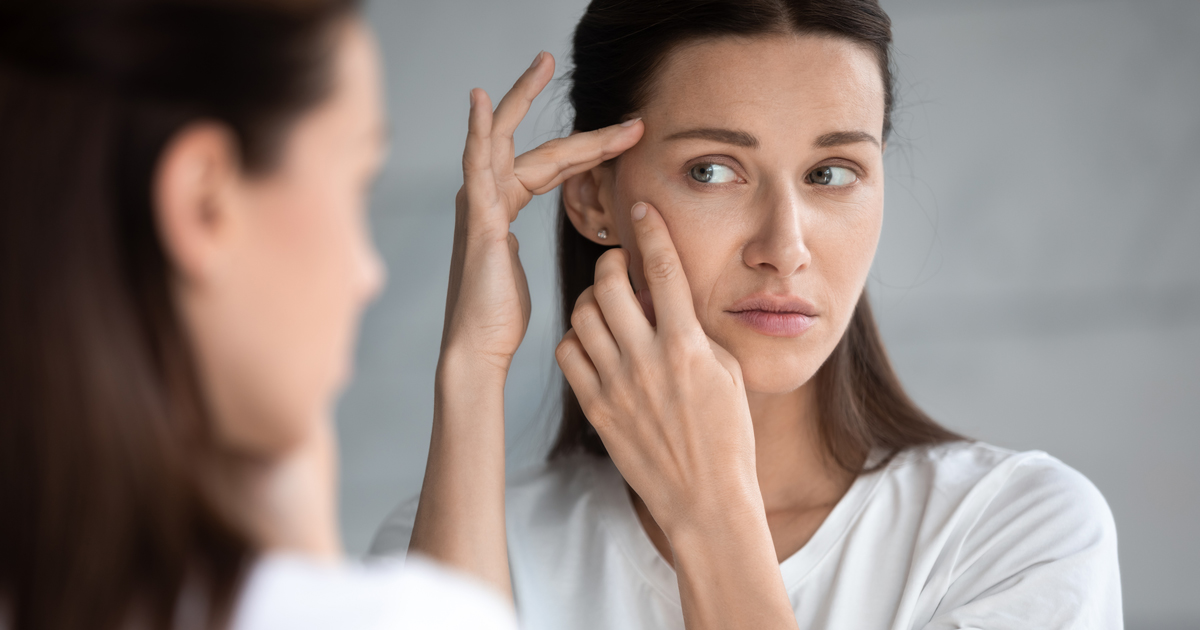 picture of a woman looking at her skin in the mirror