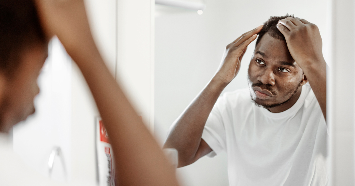 A man looking through his hair in the mirror