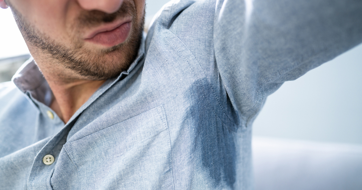 Close up of a man sweating through his dress shirt