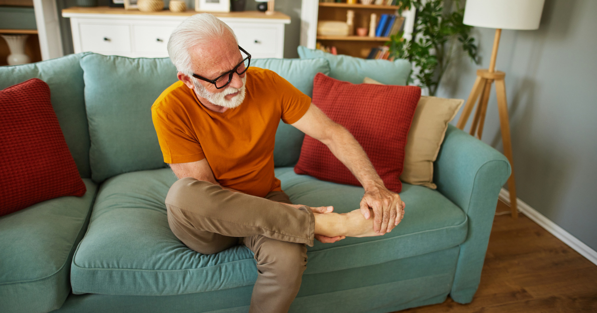 Man sitting on couch, holding foot in pain