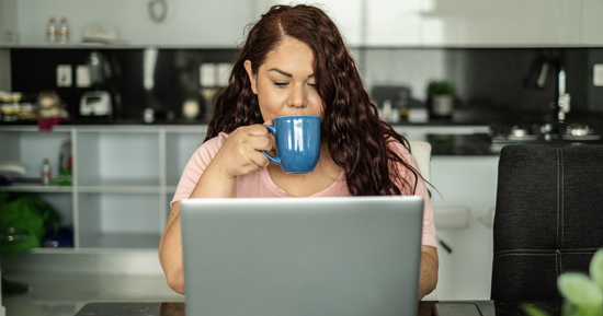 Woman drinking coffee looking at her laptop