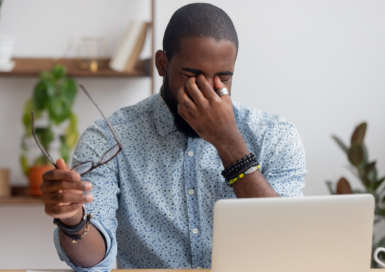 Man sitting in front of his computer rubbing his eyes