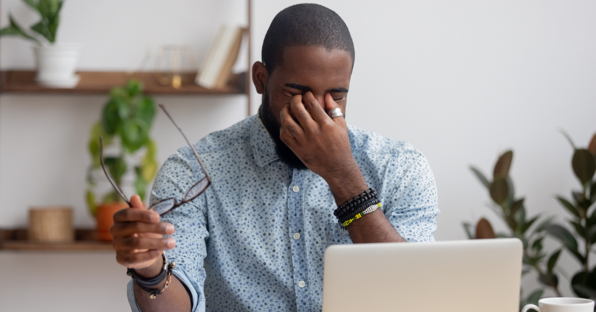 Man sitting in front of his computer rubbing his eyes