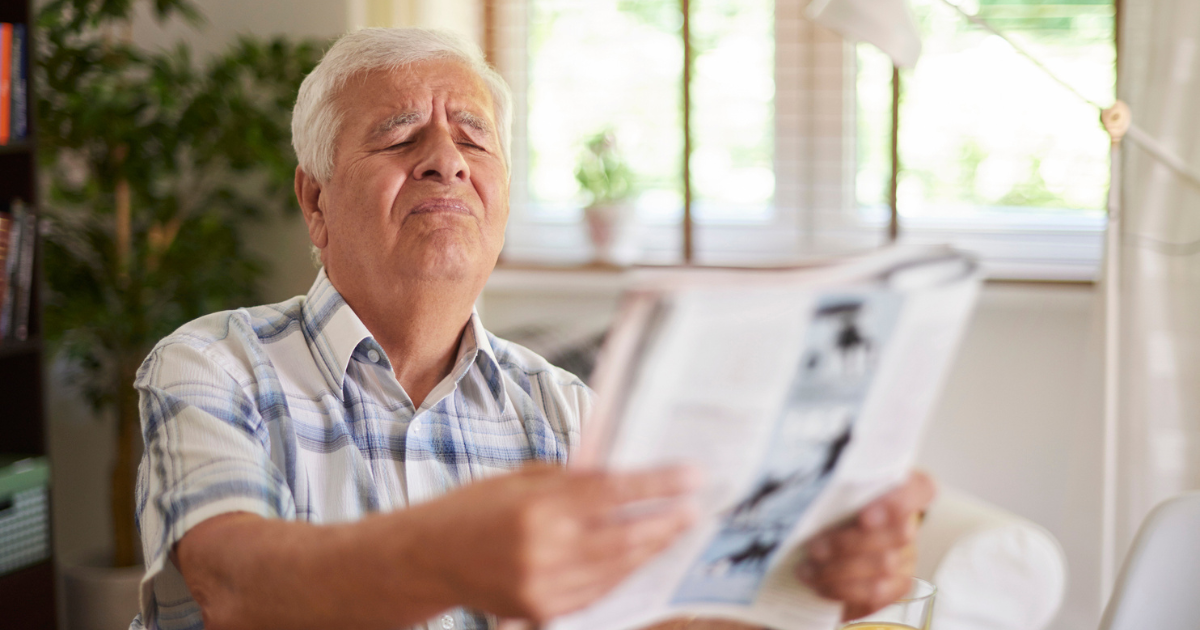 Older man squinting to read a magazine