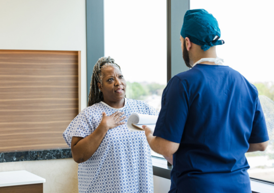 Woman with hand to her chest talking to doctor