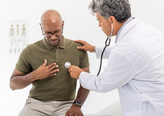 Male patient clutching his chest while a physician listens with a stethoscope