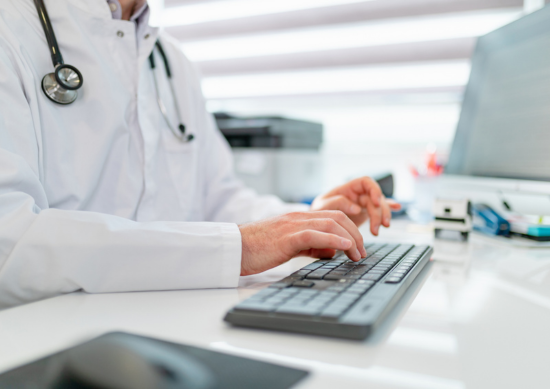 Close up of doctor typing on computer.