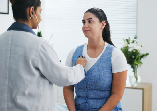 Doctor using stethoscope on young women's chest